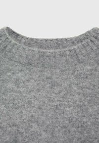 Maglione grigio con un collo rotondo a coste. Il tessuto ha una consistenza morbida e presenta un motivo sfumato con tonalità di grigio.