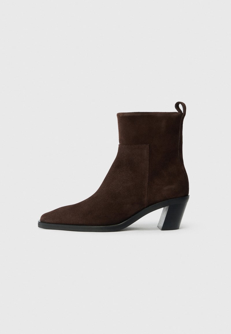 Dark brown suede ankle boot with a rounded toe, low block heel, and pull tab at the back, displayed on a plain white background.