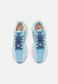 Zapatos deportivos azules con una parte superior de malla texturizada, cordones en contraste en color marino y acentos en beige. Cuenta con una suela ligera y etiqueta "Fresh Foam".