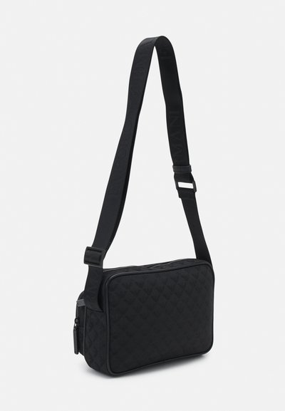 Melnas taisnstūra formas crossbody somiņa, izgatavota no struktūras materiāla, ar rāvējslēdzēja aizdari, regulējamu siksnu un izspiestu logo detaļu.
