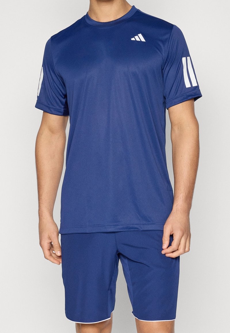 Granatowy koszulka sportowa z krótkimi rękawami, okrągłym dekoltem i białymi akcentami na rękawach. Wykonana z tkaniny odprowadzającej wilgoć. W zestawie szorty pasujące do koszulki.