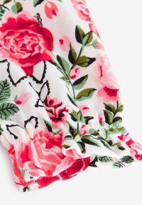 Floral cotton fabric with a white background, featuring pink and red roses, green leaves, and a gathered hem. Soft texture and vibrant colors.