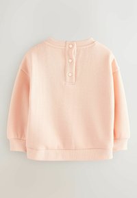 Sudadera de color rosa con cuello y puños acanalados, que presenta tres botones decorativos en la parte posterior. Tela suave y texturizada. Corte relajado.