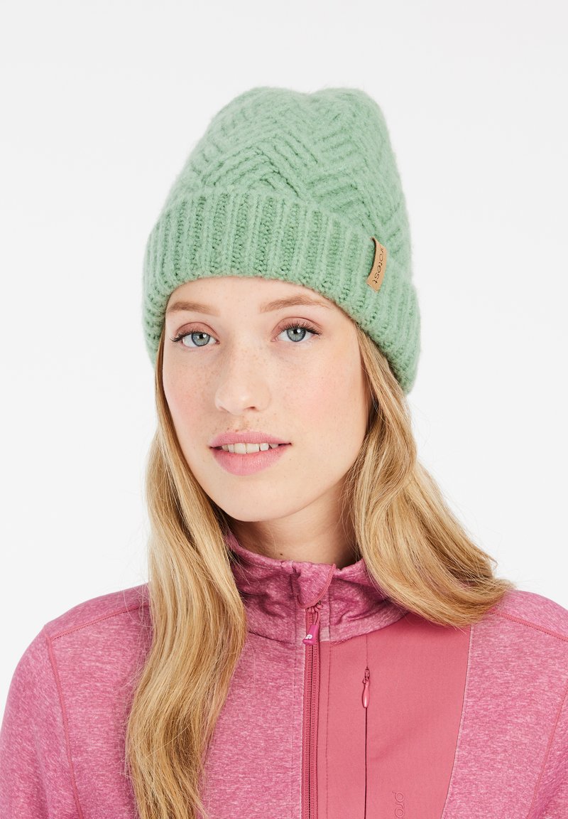 Beanie verde in maglia con un motivo geometrico testurizzato e un bordo a costine. Presenta un piccolo etichetta in pelle sul lato. Materiale morbido e caldo.
