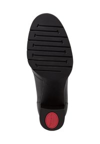 Semelle de chaussure noire avec de profondes rainures horizontales et un logo circulaire rouge marqué "Tamaris Comfort" sur le talon.