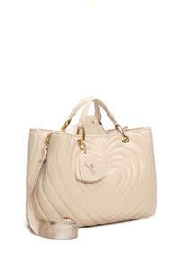 Borsa a mano in pelle beige con design a cuore trapuntato, dettagli in hardware dorato, manici superiori, tracolla staccabile e etichetta a forma di cuore.