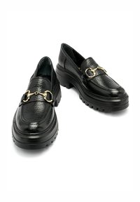 Czarne skórzane mokasyny o teksturowanym wykończeniu, zaokrąglonym nosku i grubym kauczukowym spodzie. Posiadają złoty łańcuch na przodzie, który dodaje szczegółu.