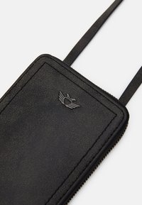 Černé kožené pouzdro na telefon s texturovaným povrchem, vybavené horním zipem a malým vyraženým logem srdce s křídly. Připojený tenký pásek.