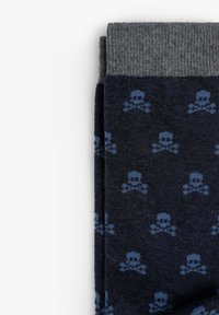 Medias azul marino con un puño gris, que muestran un patrón repetido de calaveras y huesos en color azul claro. Hechas de un material de punto suave.