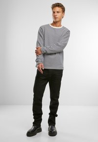 Langærmet skjorte med marineblå og hvide vandrette striber, rund halsudskæring, parret med sorte jeans og sorte chunky støvler.