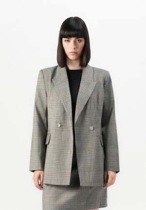 Blazer grigio a quadri con design doppiopetto, grandi rever e bottoni in tono argento. Presenta due tasche frontali e una silhouette strutturata.