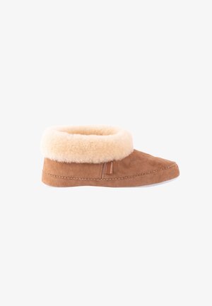 Pantofole in suede marrone chiaro con risvolto in pelliccia di pecora beige, punta arrotondata e suola in gomma bianca. Presenta un piccolo etichetta in pelle sul lato.