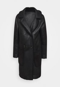 Svart shearlingkappa med bred krage, två framfickor och dubbel knappknäppning. Har en texturerad utsida och mjukt innertyg.