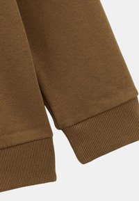 Poignet de sweat-shirt en tricot marron avec une texture côtelée. Le tissu semble doux, robuste et est soigneusement fini sans coutures visibles.