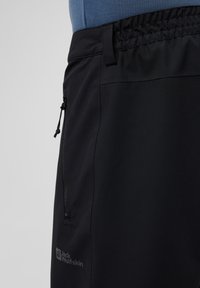 Zwarte lichtgewicht shorts met een gladde textuur, voorzien van een elastische tailleband, zijzak met rits en een logo gedrukt op het linkerpijpen.