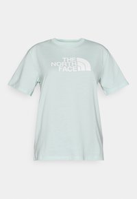 Μέντα πράσινο μπλουζάκι από μαλακό βαμβάκι, με μεγάλο λευκό γραφικό λογότυπο στο στήθος. Κλασικός στρογγυλός λαιμός και κοντά μανίκια.