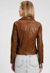 Giacca in pelle marrone con un design aderente, cuciture visibili e polsini con zip. Presenta un colletto classico e dettagli accentuati sulle spalle.