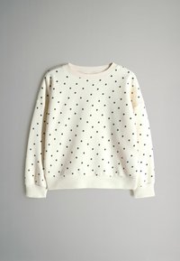 Krémová mikina s černými puntíky, vroubkovaným výstřihem a manžetami. Mírně volný střih s kleslými ramenními švy.