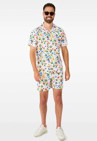 Bunt bedrucktes Kurzarmhemd und passende Shorts, mit einem weißen Hintergrund, auf dem Regenbogen-, Stern- und Kreis-Muster zu sehen sind. Der Stoff wirkt leicht.