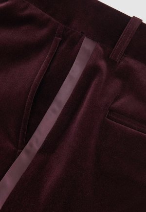 Bordeaux velour stof med en glat tekstur, der har et sidestykke i satinfinish og en baglomme detalje. Slank, skræddersyet design.