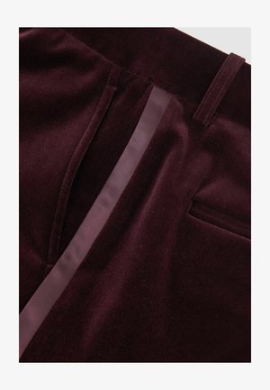 Burgundská sametová látka se hladkým povrchem, s bočním panelem v saténovém provedení a detailem zadní kapsy. Úzký, dobře padnoucí design.