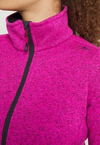 Giacca in pile di un vivace colore rosa con colletto alto. Presenta una cerniera nera come accentuazione e un motivo testurizzato a maglia. Logo sulla spalla.