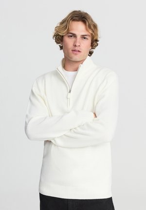 Maglione bianco a maglia con zip a quarti, polsini e orlo rigati, caratterizzato da una consistenza morbida e una vestibilità rilassata.