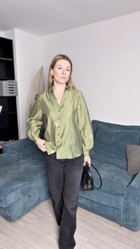 Πράσινο σατέν πουκάμισο με κουμπιά και χρυσά ανθισμένα διακοσμητικά, μακριά μανίκια, συνδυασμένο με μαύρο παντελόνι καμπάνα και μικρή μαύρη τσάντα.