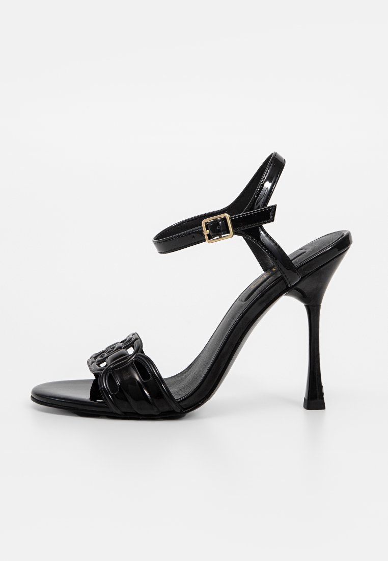 Schwarze Lackleder-High Heelsandale mit Knöchelriemen, offener Zehenpartie und dekorativem Schleifendetail auf der Vorderseite, ausgestattet mit einem schlanken Stiletto-Absatz.