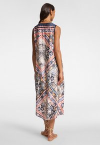 Langes, ärmelloses Kleid aus einem blauen und beigen gemusterten Stoff mit geometrischen Designs und einem High-Low-Saum, akzentuiert mit rosa und korallenfarbenen Tönen.
