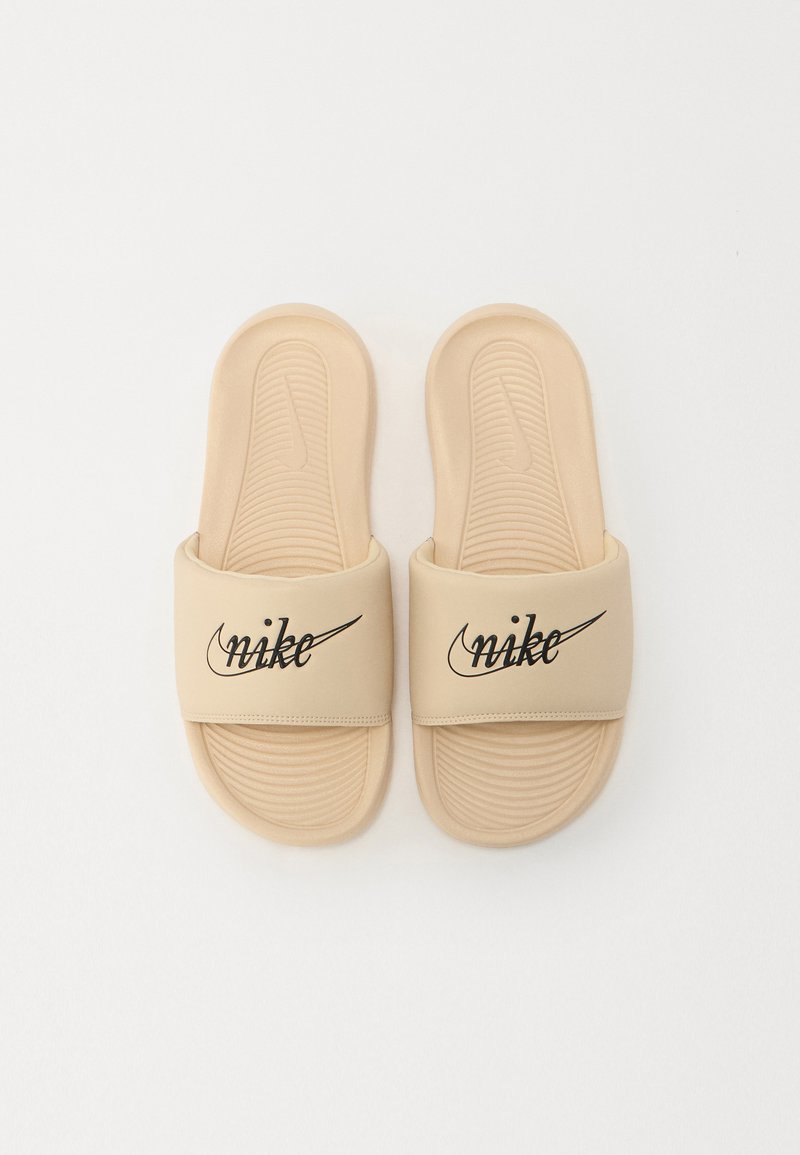 Sandales à glissière beiges avec une semelle texturée et une large sangle arborant un logo Nike noir. Matériau lisse sans accents visibles.