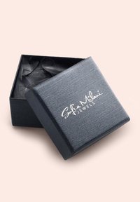 Schwarze strukturierte Schmuckbox mit einem leicht geöffneten Deckel, auf dem in weißer, geschwungener Schrift "Sofia Milani JEWELS" steht.