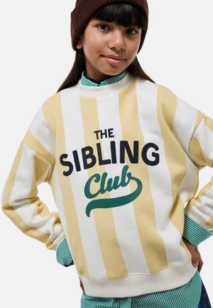 Sweatshirt à rayures blanches et jaunes avec "THE SIBLING Club" imprimé en noir et vert, doté d'un col rond et de poignets côtelés.