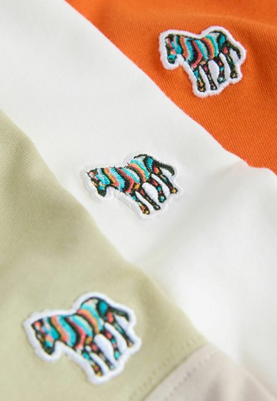 Tela de algodón en secciones verdes, blancas y naranjas que presenta diseños de cebras bordadas en colores vibrantes, con detalles de puntadas texturizadas.