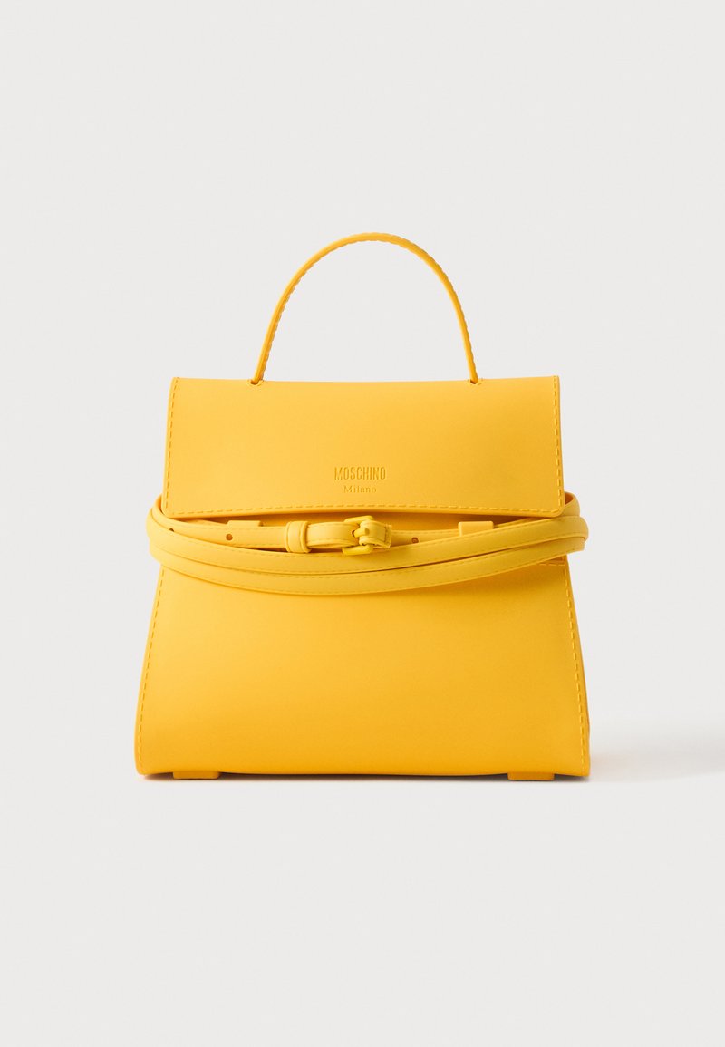 Sac à main Moschino jaune avec poignée supérieure et détail de ceinture avec boucle enveloppée sur le rabat avant, sur fond blanc.