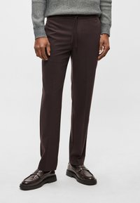 Calças castanho-escuro sob medida com cintura elástica e cordão ajustável, apresentando tecido suave e corte reto nas pernas.