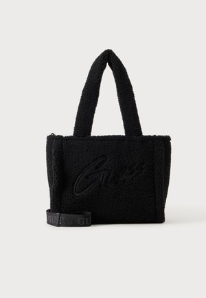 Sac cabas noir texturé en tissu doux avec deux poignées, avec un logo discret "Guess" et une sangle brandée amovible.