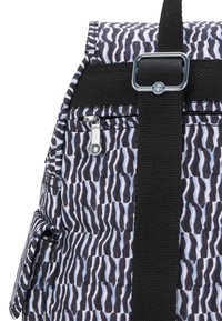 Mochila Kipling con un patrón ondulado azul y negro, con una correa negra, accesorios plateados y múltiples bolsillos con cremallera.
