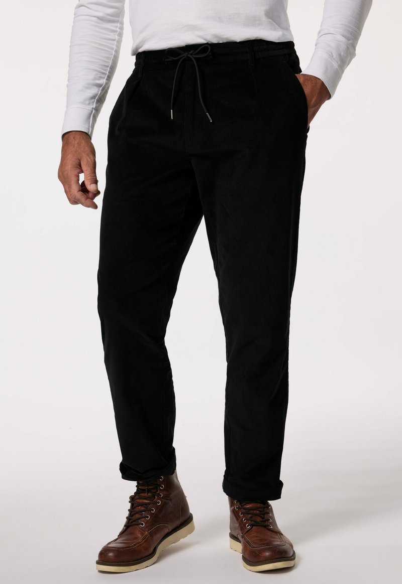 Zwarte corduroy broek met een trekkoord taille en zijzakken, heeft een slim fit en zachte textuur. Gecombineerd met bruine leren laarzen.