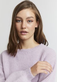 Hellblauer Strickpullover mit geripptem Muster, Rundhalsausschnitt und langen Ärmeln. Der Stoff wirkt weich und leicht oversized.