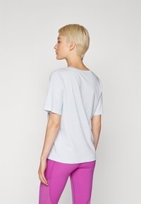 Light blue short-sleeve t-shirt with a round neckline, soft fabric, relaxed fit, displayed with purple leggings.