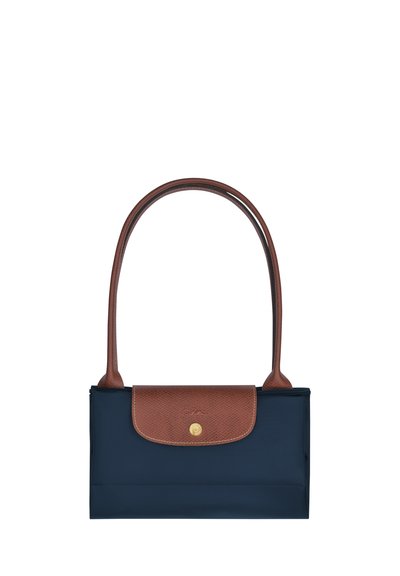 Navy blue fabric tote bag with a brown leather flap, gold hardware, and two long brown straps. Smooth texture with a simple design.
