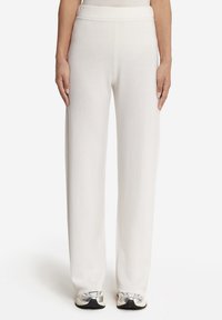 Vita vida byxor i mjukt tyg med elastisk midja, som visar en slät textur utan synliga mönster eller detaljer.