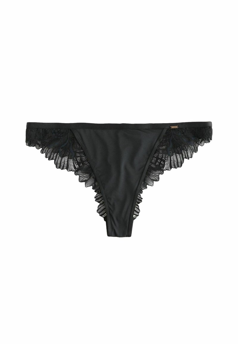 Zwarte string gemaakt van gladde stof met kantafwerking aan de zijkanten. Beschikt over golvende randen en een klein logo-label op de tailleband.