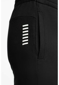 Pantaloni da jogging neri con tasca laterale, caratterizzati da strisce bianche verticali come accento di design. Realizzati in tessuto morbido e strutturato per il massimo comfort.