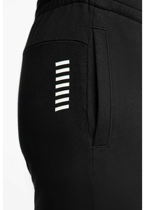 Pantaloni da jogging neri con tasca laterale, caratterizzati da strisce bianche verticali come accento di design. Realizzati in tessuto morbido e strutturato per il massimo comfort.