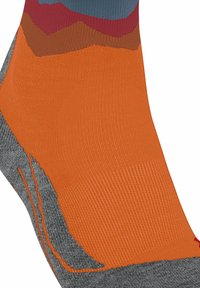 Primo piano di una calza con il piede arancione, il tallone grigio e il polsino multicolore in tessuto lavorato a maglia blu, rosso e marrone.