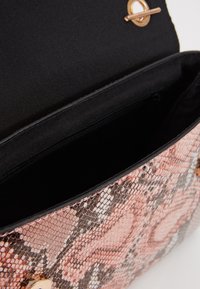 Borsa a tracolla in pelle sintetica effetto rettile rosa e grigia con chiusura dorata, dotata di un interno in tessuto nero e una tasca con zip all'interno.