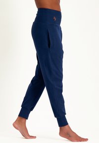 Marineblaue Jogginghosen aus weichem Stoff, mit hohem Bund, seitlichen Taschen und Bündchen an den Knöcheln. Besticktes Logo am Bund.