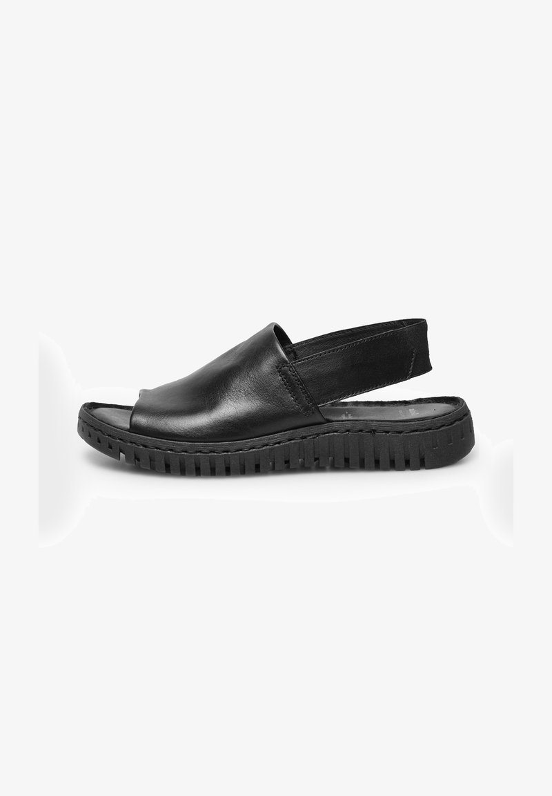Sandalo slingback in pelle nera con punta aperta, suola in gomma testurizzata e design minimalista. Presenta un tacco leggermente rialzato.